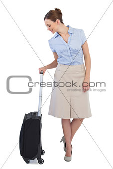 Cheerful classy businesswoman posing with suitcase