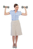Strong businesswoman posing with dumbbells looking at camera