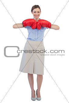 Cheerful businesswoman posing with red boxing gloves