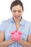 Astonished businesswoman posing with piggy bank
