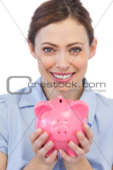 Businesswoman showing her piggy bank to camera
