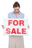 Happy estate agent posing with for sale sign