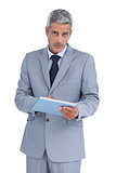 Serious businessman using tablet pc looking at camera