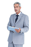 Serious businessman using tablet pc looking away