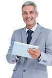Happy businessman using tablet pc looking at camera