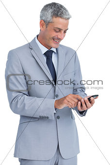Cheerful businessman sending text message
