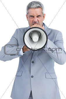 Furious businessman posing with loudspeaker and looking at camera