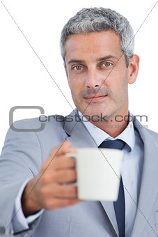 Handsome businessman offering cup of coffee
