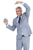 Cheerful businessman pointing out alarm clock