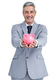 Joyful businessman holding piggy bank