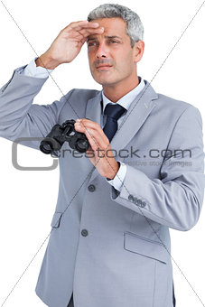 Businessman posing with binoculars and looking away