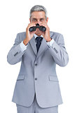 Curious businessman observing through binoculars
