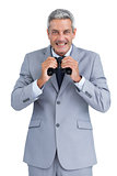 Cheerful businessman observing with binoculars