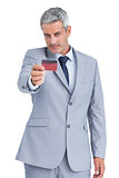 Handsome businessman holding and looking at credit card