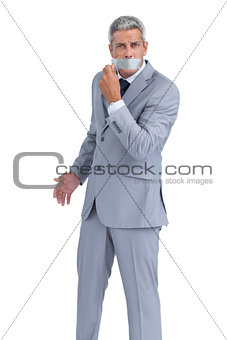 Businessman taking off adhesive tape on mouth