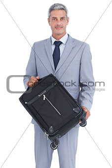 Handsome businessman carrying suitcase and looking at camera