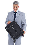 Handsome businessman carrying and looking at his suitcase