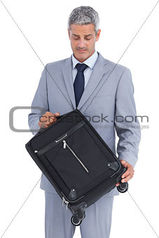 Handsome businessman carrying and looking at his suitcase