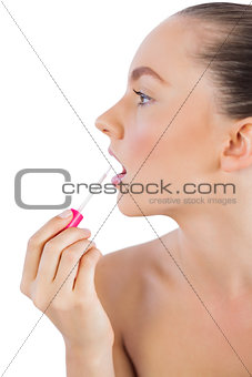 Profile of woman putting lip gloss on her lips