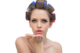 Young model in hair rollers blowing a kiss