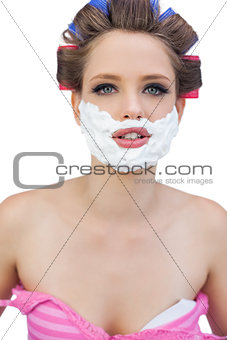 Young model in hair curlers with shaving foam posing
