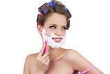 Cheerful lady in hair curlers posing with razor