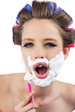 Young model in hair curlers posing while shaving