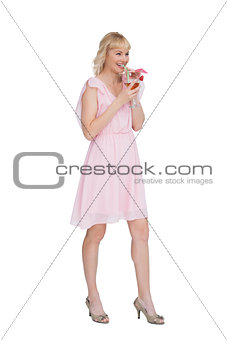 Cheerful blonde posing while drinking cocktail