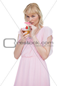 Pretty blond woman drinking cocktail and looking at camera
