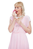 Pretty blond woman with cocktail eating fruits