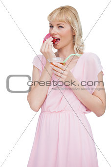 Pretty blond woman with cocktail eating fruits