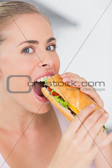 Happy woman eating sandwich