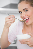 Pretty blonde woman eating bowl of cereal