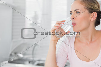 Pensive blond woman drinking water