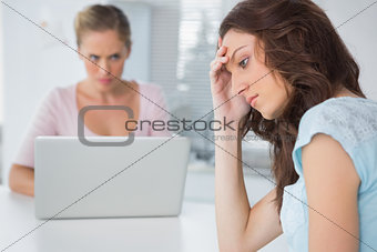 Upset woman thinking while her angry friend is staring at her