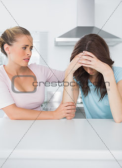Worried woman looking at her upset friend
