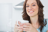 Cheerful brunette holding cup of coffee