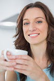 Radiant brunette holding cup of coffee