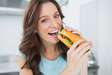 Cheerful brunette eating sandwich