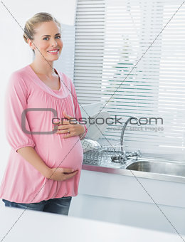 Cheerful expecting woman touching her belly