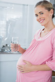 Expecting woman affectionately touching her belly and drinking water