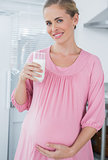 Cheerful expecting woman drinking milk
