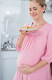 Happy expecting woman holding biscuits
