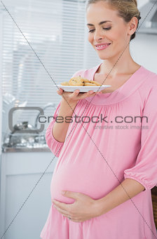 Happy expecting woman holding biscuits