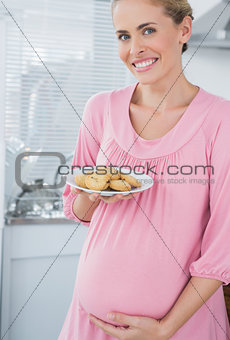 Happy expecting woman offering biscuits