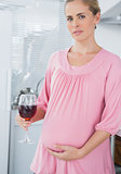Expecting woman having glass of red wine