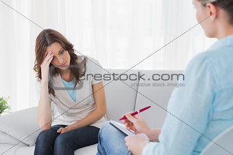 Worried woman sitting while therapist looking at her