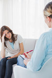 Worried woman sitting with therapist taking notes