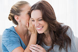 Woman revealing secret to her friend smiling