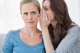 Blond woman hearing a secret from her friend
